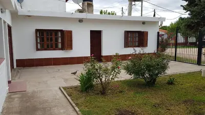 a white house with two windows and a cat in the yard at Casa Kassel in Villa Cura Brochero