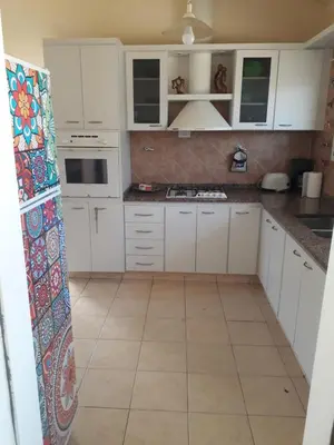 a kitchen with white cabinets and a tile floor at Casa Anémona in Merlo