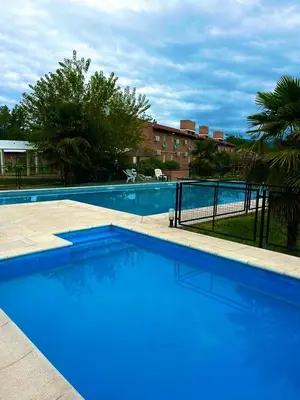a large blue swimming pool with a fence around it at Hotel Aimara in Mina Clavero