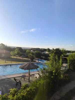 a swimming pool with an umbrella and chairs next to it at Hotel Aimara in Mina Clavero