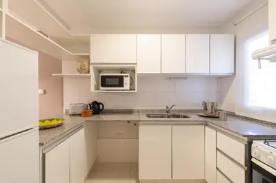a white kitchen with white cabinets and a sink at AT Suites in Cordoba