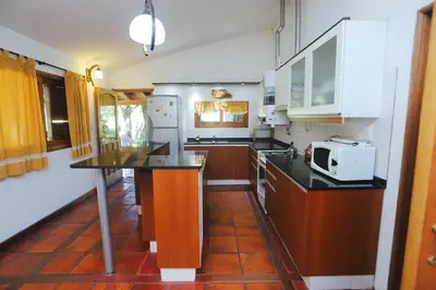a kitchen with white appliances and a black counter top at Cabaña Modestita - FINCA PUDUAM in Villa General Belgrano
