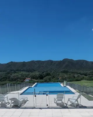 a swimming pool with several chairs at Cabaña Modestita - FINCA PUDUAM in Villa General Belgrano