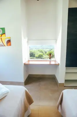 a room with two beds and a window with a view at Cabaña Sol - FINCA PUDUAM in Villa General Belgrano