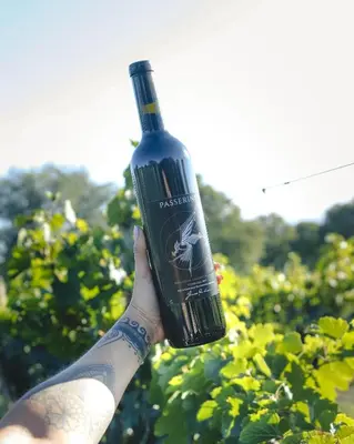 a person holding a wine bottle in their hand at Cabaña Sol - FINCA PUDUAM in Villa General Belgrano