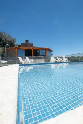 a swimming pool with chairs and a house at Cabaña Sol - FINCA PUDUAM in Villa General Belgrano