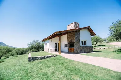 a small stone house on a grassy hill at Cabaña Sol - FINCA PUDUAM in Villa General Belgrano