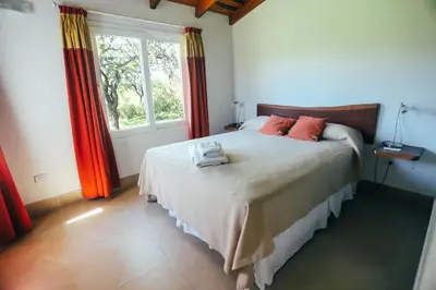 a bedroom with a bed with red curtains and a window at Cabaña Sol - FINCA PUDUAM in Villa General Belgrano
