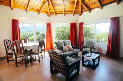 a living room with a table and red curtains at Cabaña Sol - FINCA PUDUAM in Villa General Belgrano