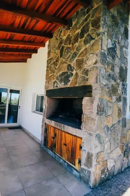 a stone fireplace in a house with a roof at Cabaña Sol - FINCA PUDUAM in Villa General Belgrano