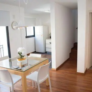 a dining room with a glass table and white chairs at Guemes Apart Nueva Cordoba in Cordoba