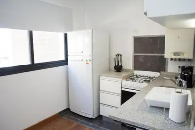 a kitchen with a white refrigerator and a stove at Guemes Apart Nueva Cordoba in Cordoba
