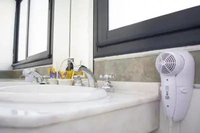 a bathroom sink with a hair dryer next to a mirror at Guemes Apart Nueva Cordoba in Cordoba