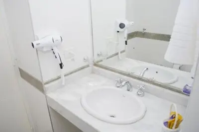 a white bathroom with a sink and a mirror at Guemes Apart Nueva Cordoba in Cordoba