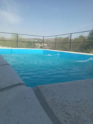 a swimming pool with blue water and a fence at Casa de Alquiler 1 in Tanti