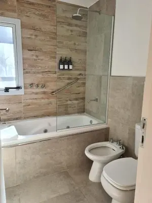 a bathroom with a tub and a toilet and a shower at Be mas apartamentos boutique Villa Gral Belgrano in Villa General Belgrano