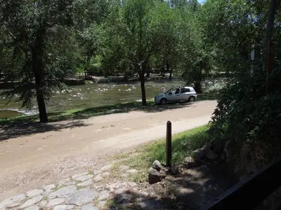 a car parked on a dirt road next to a river at Cabañas La Pirca in Santa Rosa de Calamuchita