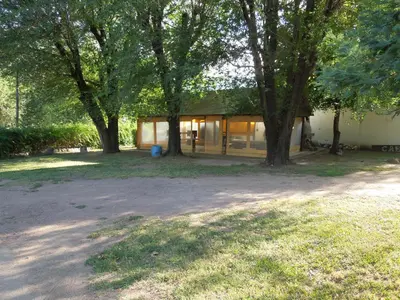 a house with a group of trees in front of it at Cabañas La Pirca in Santa Rosa de Calamuchita