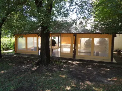 a house with glass doors and a tree at Cabañas La Pirca in Santa Rosa de Calamuchita