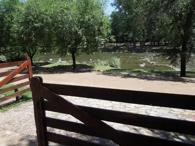a fence in front of a river with trees at Cabañas La Pirca in Santa Rosa de Calamuchita