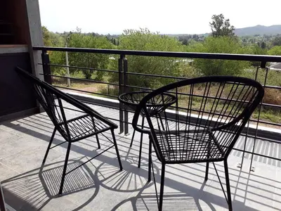 two chairs and a table on a balcony at Luces Casas de Montaña in Villa del Dique