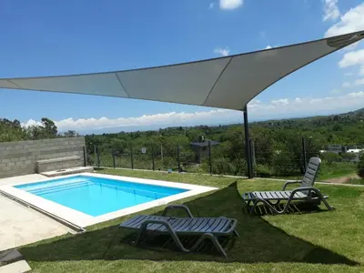 a pool with two chairs and an umbrella at Luces Casas de Montaña in Villa del Dique