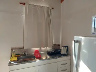 a kitchen counter with a sink and a refrigerator at Loma Alta Apart in Villa Yacanto