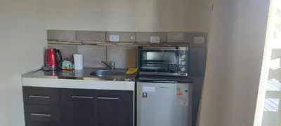a kitchen with a sink and a microwave and a refrigerator at Loma Alta Apart in Villa Yacanto