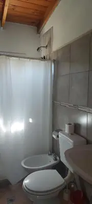 a bathroom with a white toilet and a sink at Loma Alta Apart in Villa Yacanto