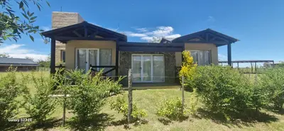 a small house in a field with bushes at Loma Alta Apart in Villa Yacanto