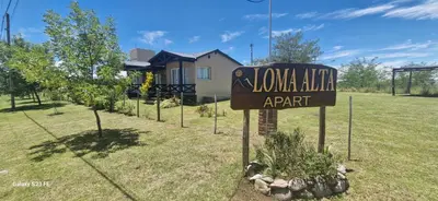 a sign in front of a yard with a house at Loma Alta Apart in Villa Yacanto