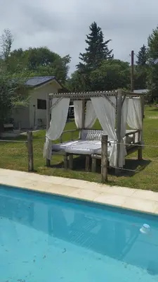 a bench with curtains next to a swimming pool at Las Brisas casas de campo un lugar para soñar in San Antonio de Arredondo