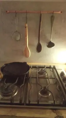 a stove top with cooking utensils hanging above it at I Víla in Villa Carlos Paz