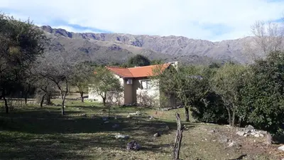 a small house in a field with mountains in the background at ASM CASA III in Merlo