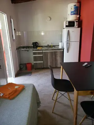 a kitchen with a table and a white refrigerator at Descanso Serrano in Santa Rosa de Calamuchita