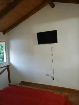 a bedroom with a flat screen tv on the wall at Descanso Serrano in Santa Rosa de Calamuchita