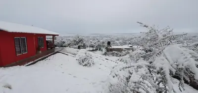 a snow covered yard next to a red house at Terrazas de Estancia in Villa Carlos Paz