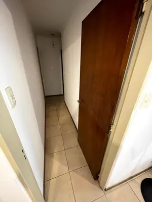 a hallway with a wooden door and a tile floor at Amplio departamento ZONA CENTRO (2) in Cordoba