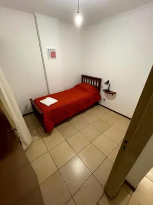 a small bedroom with a red bed and a tiled floor at Amplio departamento ZONA CENTRO (2) in Cordoba