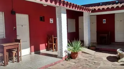 a red house with white doors and a patio at Amanitas Posada in Villa Carlos Paz