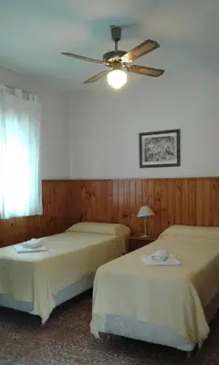 two beds in a room with a ceiling fan at Amanitas Posada in Villa Carlos Paz