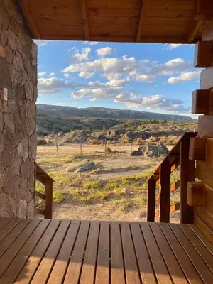 a wooden porch with a view of a field at Alma Serrana - Suites de montaña! in La Cumbrecita