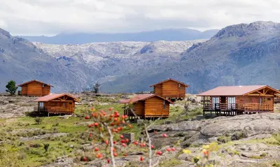 a group of wooden huts on a mountain at Alma Serrana - Suites de montaña! in La Cumbrecita