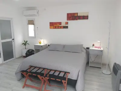 a white bedroom with a bed and a table at Love Sunset in Villa Carlos Paz
