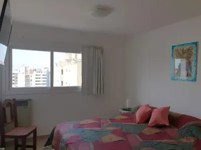 a bedroom with a bed with a colorful quilt and a window at Rosa de los vientos - Cofico in Cordoba