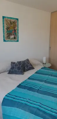 a bed with a blue blanket and a picture on the wall at Rosa de los vientos - Cofico in Cordoba