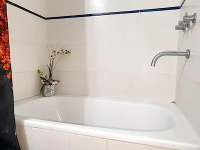 a white bath tub in a bathroom with a vase of flowers at Rosa de los vientos - Cofico in Cordoba