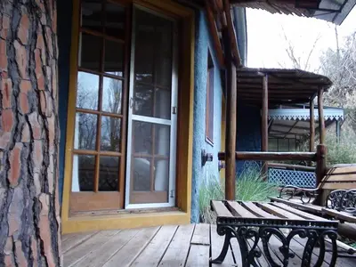 a wooden porch with a bench and a door at Manantial Hostería & Cabañas in Nono