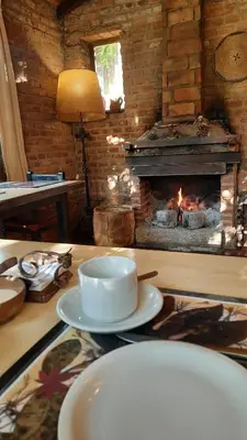 a table with plates and a fireplace in a room at Manantial Hostería & Cabañas in Nono