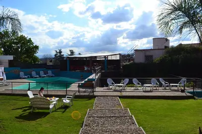 a person sitting in a chair next to a swimming pool at Hotel Montana by CPH in Villa Carlos Paz